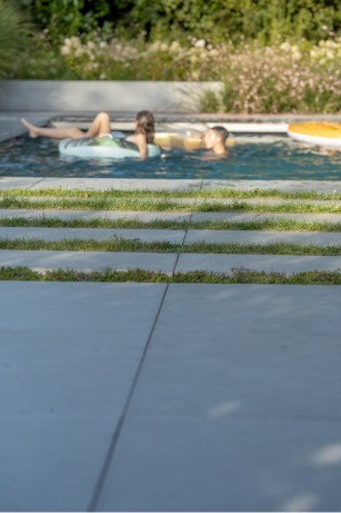 Pose de mégadalles en béton autour d'une piscine dans un jardin à Spy