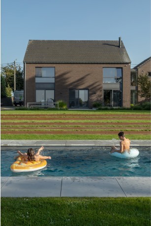 Piscine avec une pose de marches en acier corten dans un jardin à Gesves