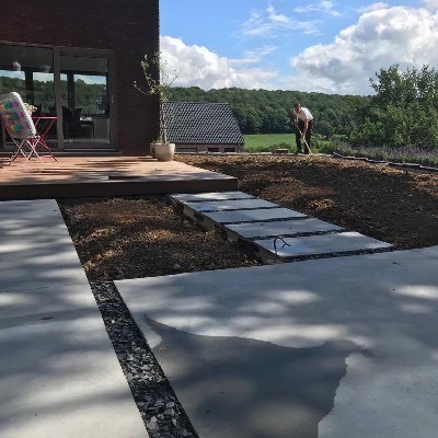 Terrasse en béton lissé avec pas japonais et plantations à Profondeville